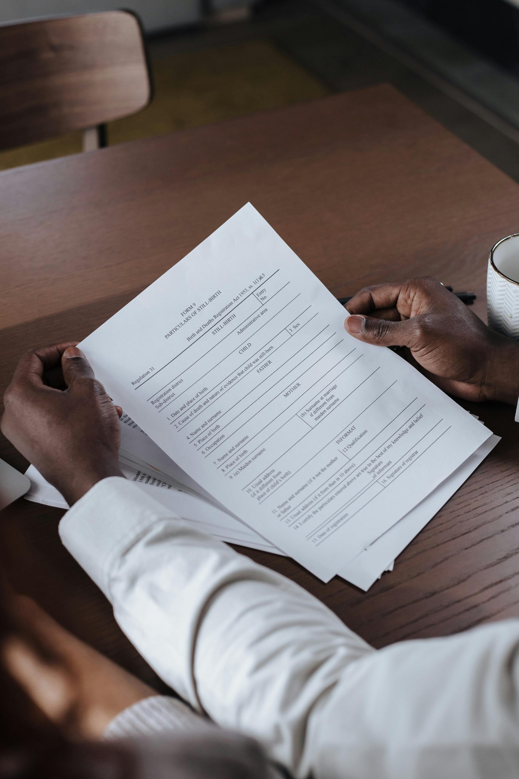 Close-up of a man holding and reviewing business documents at a wooden table.